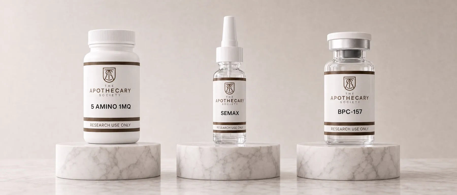 A capsule bottle, a nasal spray and a vial from The Apothecary Society on marble plinths